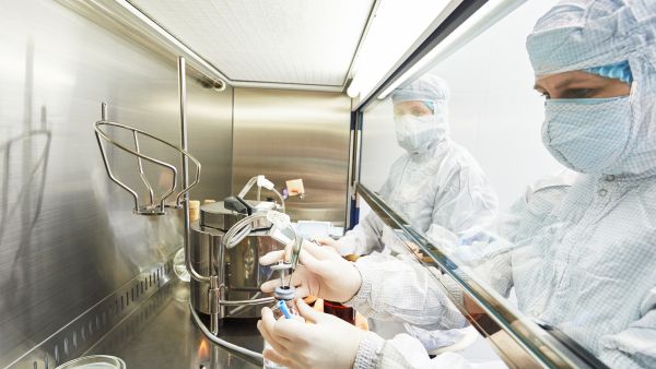 Scientists in protective equipment working on microbiological research