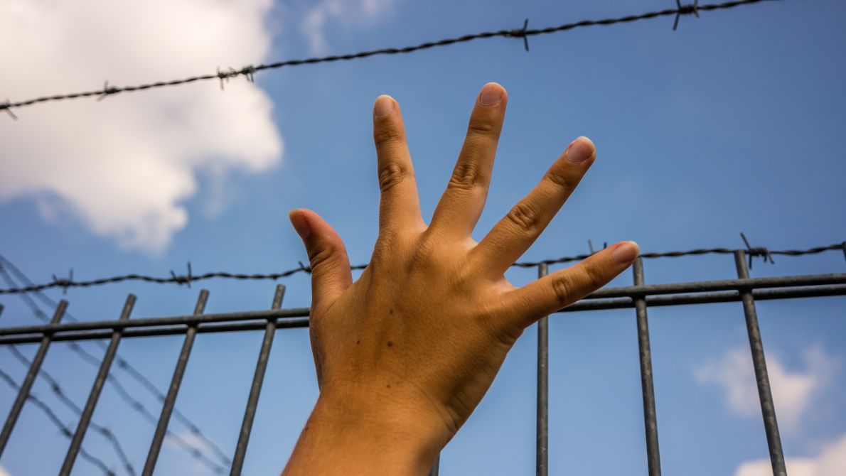hand by barbed wire border