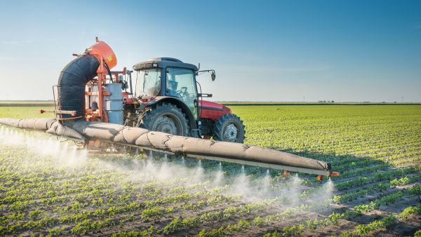 Tractor spraying pesticide on farm