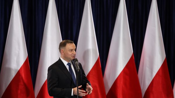 Polish president Andrzej Duda speaking in front of a row of Polish flags