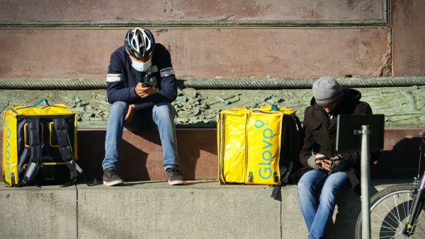 Gig economy delivery workers wait for work in Milan