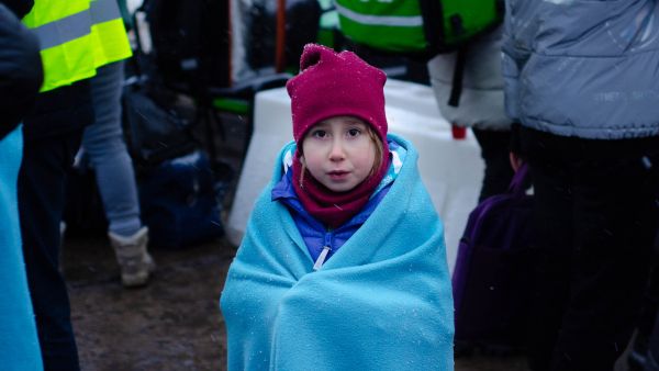 Ukrainian girl in a blanket fleeing the war at the Siret border in Romania